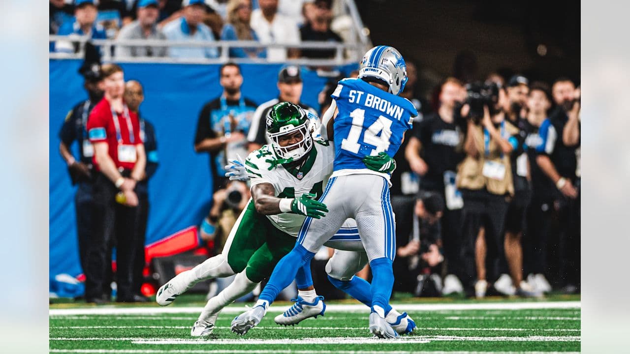 A Jets defender tackles a Lions receiver on the field in Detroit.